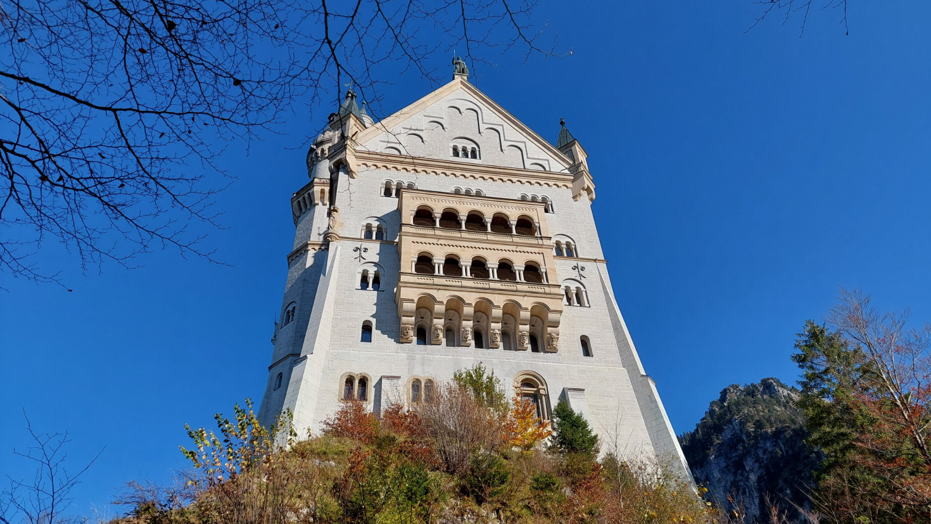 Neuschwanstein Castle's tower seen from below, autumn colors around it