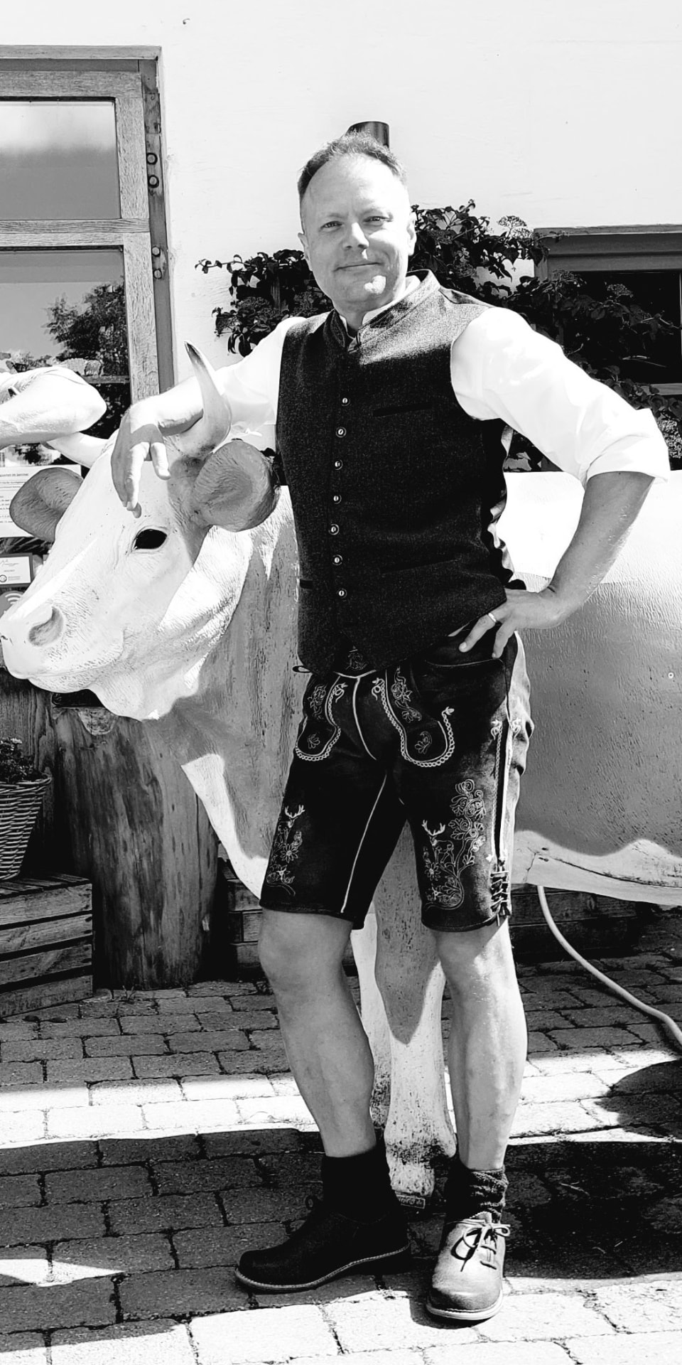 Martin Hakel standing next to a life-size cow statue in traditional Bavarian dress